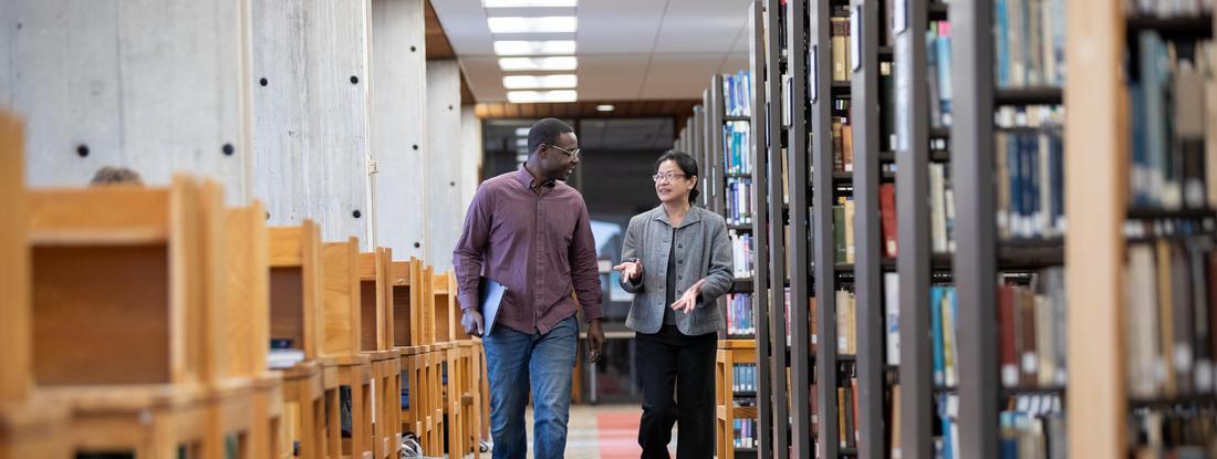 侫Ƶ Student and Professor walking in Bush library